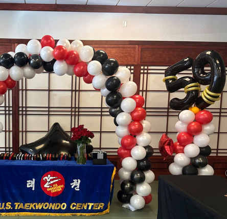 Red, white and black balloon arch and column decorations for a martial arts event