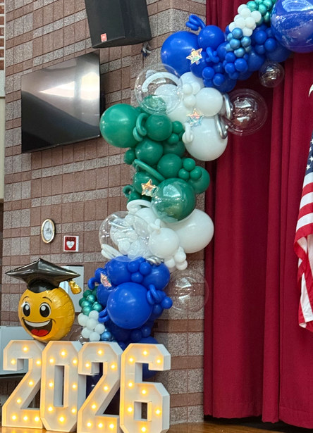 Green, blue and white custom balloon column displayed beside a stage